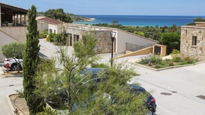 A coastal building with a stone facade, a covered outdoor area, and a view of the sea. - Odalys Residence Les Hameaux de Capra Scorsa (Belgodere)