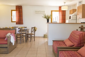 Un espacio habitable compacto con kitchenette, comedor y sofá.