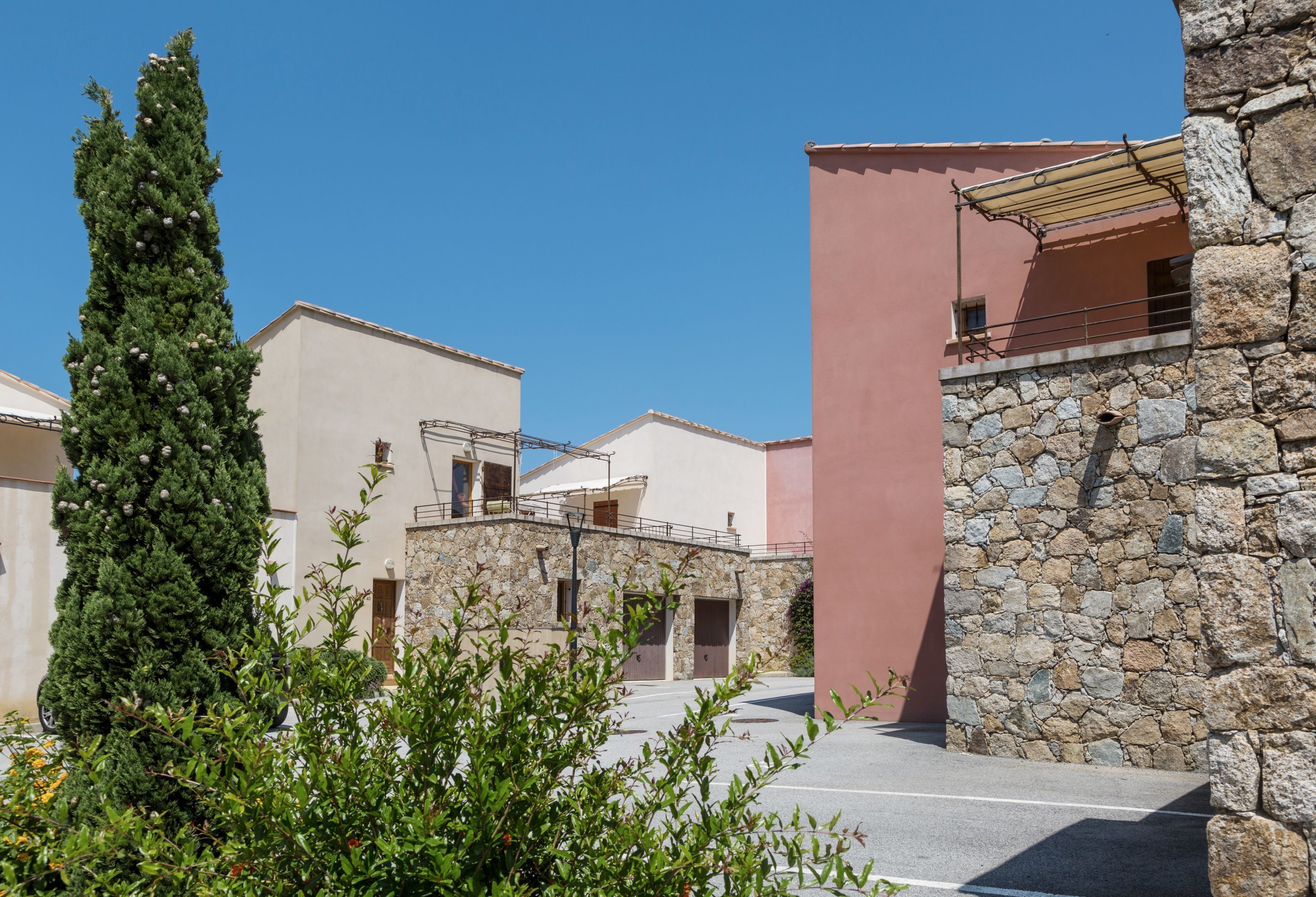 A building with a stone facade, a pink wall, and a clear blue sky.