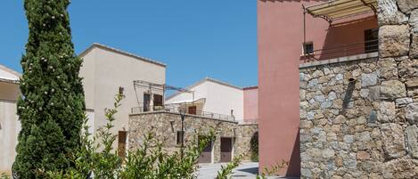 A building with a stone facade, a pink wall, and a clear blue sky.