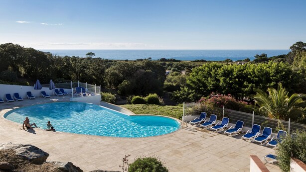 A swimming pool with blue lounge chairs and a view of the sea. - Odalys Residence Les Hameaux de Capra Scorsa (Belgodere)