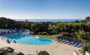 A swimming pool with blue lounge chairs and a view of the sea. - Odalys Residence Les Hameaux de Capra Scorsa (Belgodere)
