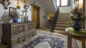 A staircase with a wooden railing, a patterned rug, and a wooden cabinet with decorative carvings.