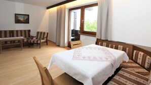 A hotel room with a bed, a sofa, a chair, a small table, and a window with curtains.