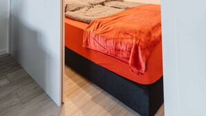 A bedroom with a bed, a nightstand, and a wall-mounted light. - Business Apartments Ratingen West (Ratingen)