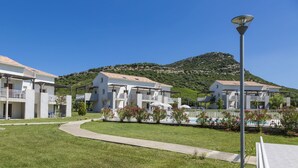 A resort with multiple-story buildings, a pathway, and a mountain backdrop. - Résidence Odalys Casa d'Orinaju (Oletta)