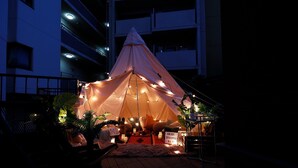 A tent with string lights, a table with a sign, and plants.