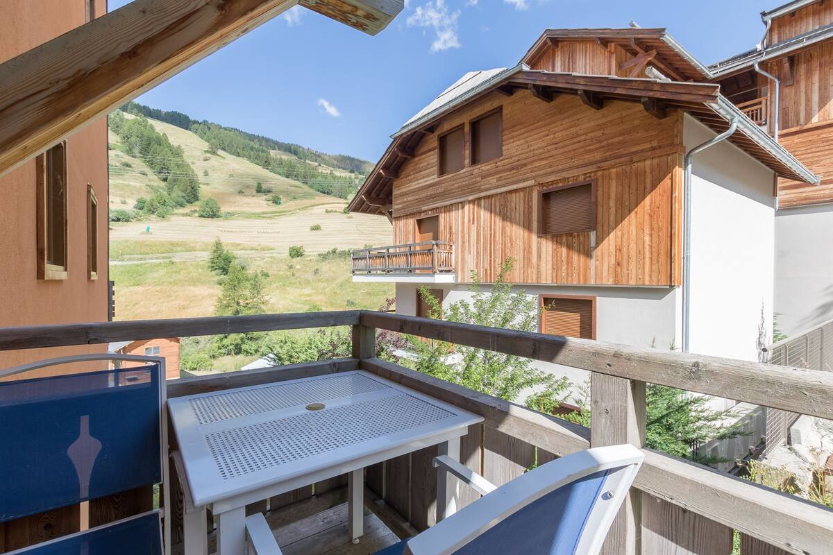 A wooden chalet with a balcony overlooking a mountainous landscape.