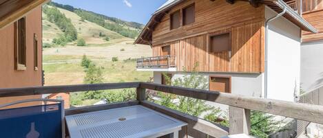 A wooden chalet with a balcony overlooking a mountainous landscape.