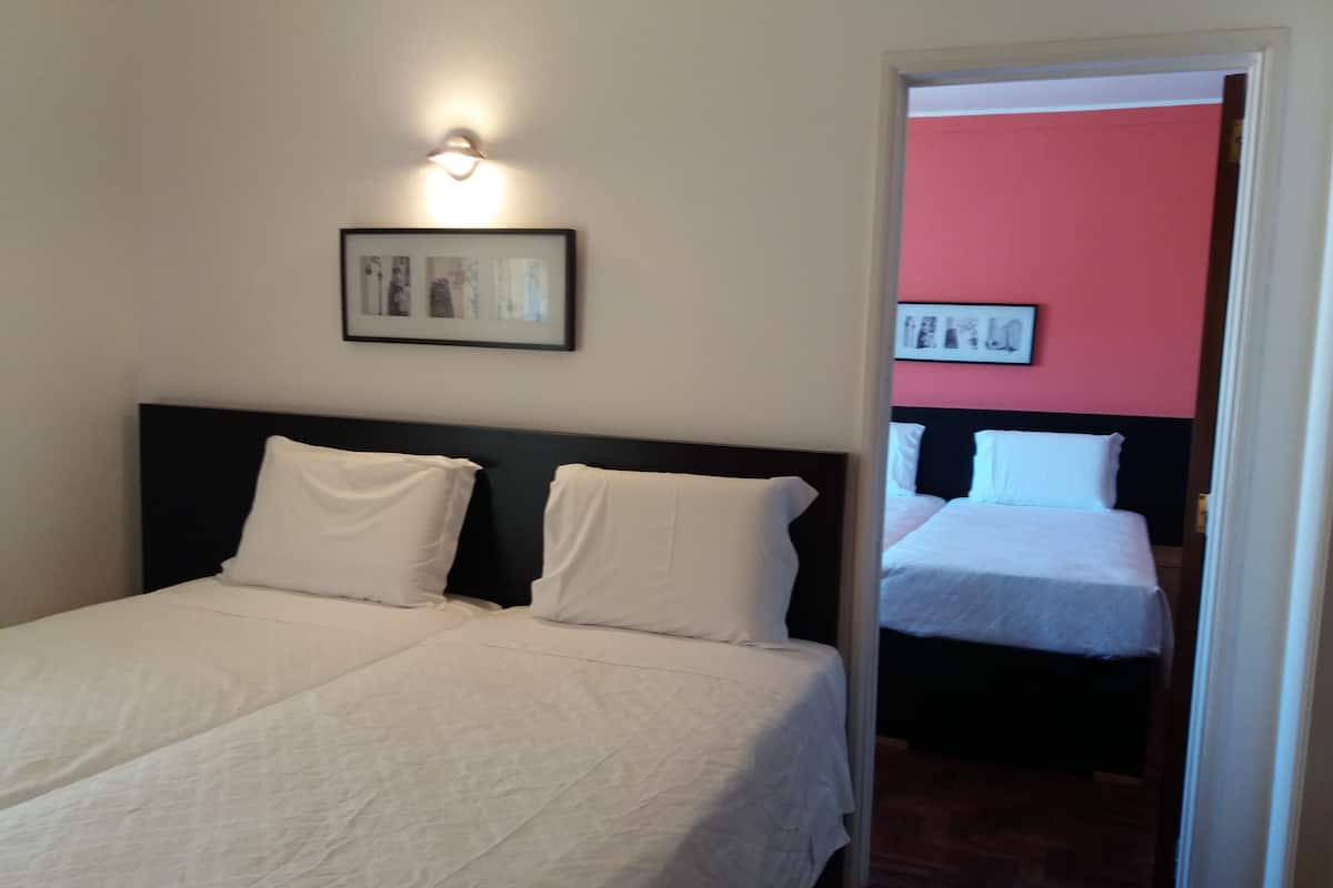 A hotel room with a bed, a nightstand, and a wall-mounted light fixture.