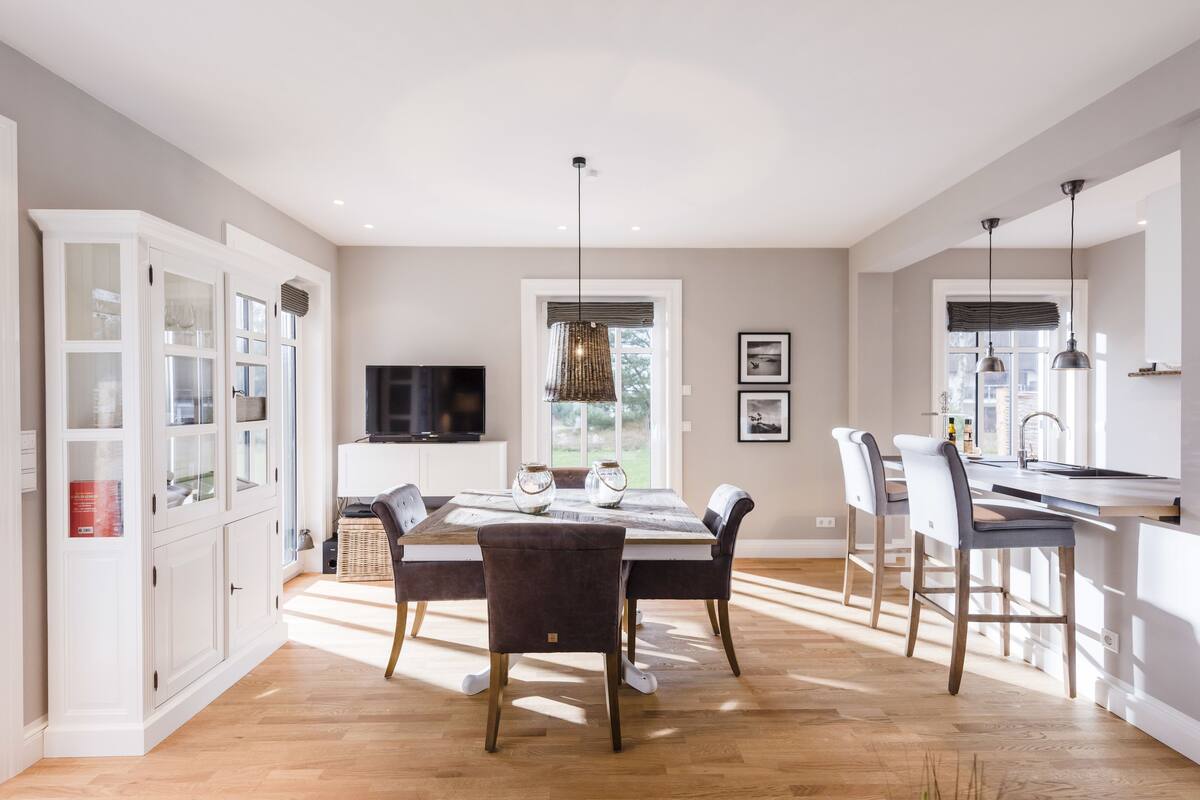 Una cocina moderna con comedor, piso de madera y un amplio ventanal que proporciona luz natural.