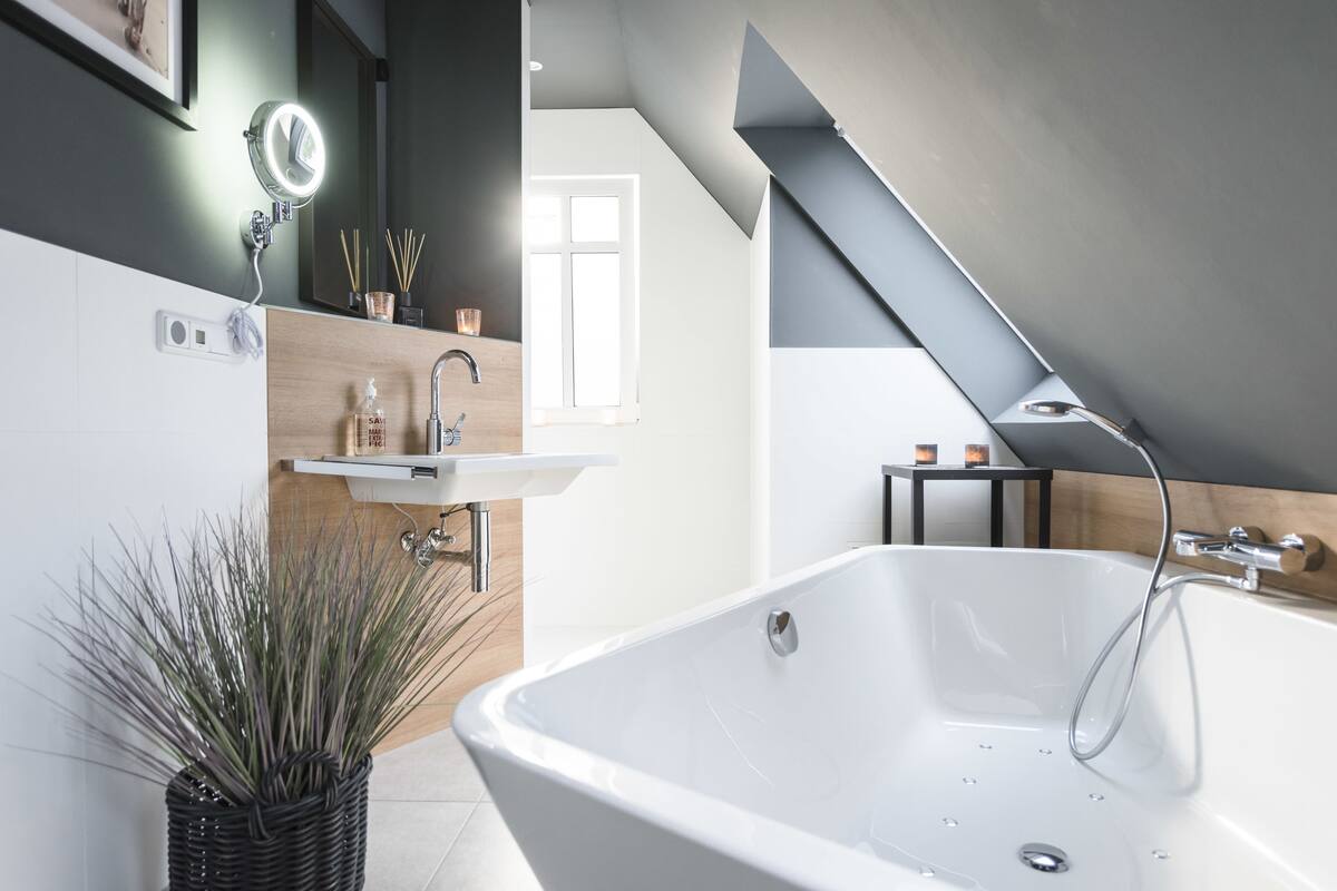 Un baño moderno con una bañera independiente, un tocador con espejo y una ventana que proporciona luz natural.