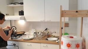 Une cuisine avec des armoires blanches, une chaise en bois, un évier et divers ustensiles de cuisine.