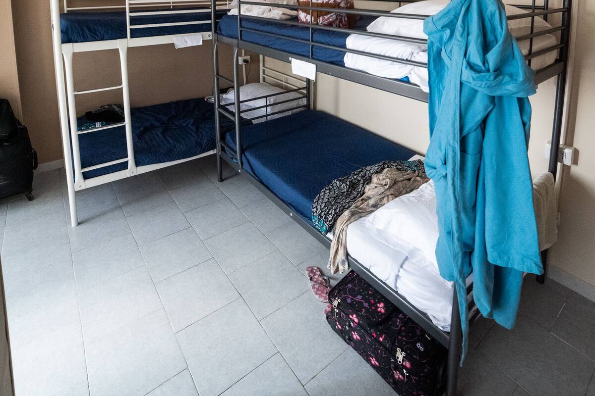 A bunk bed room with a ceiling fan, a desk, and a suitcase on the floor.