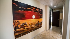 Un couloir orné d’un grand tableau représentant un coucher de soleil.