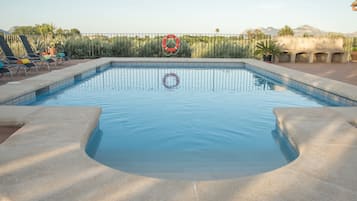 Relax by the serene pool surrounded by lush natural scenery and lounge chairs.