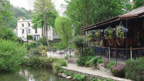 A riverside setting with a restaurant featuring outdoor seating and hanging flower baskets. - (101)Beautiful Apartment in Landmark Cotswold Grade II Listed Georgian House -  (Nailsworth)