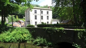 A white building with "RAILWAY HOTEL" signage, a stone bridge, and a pond with vegetation. - (101)Beautiful Apartment in Landmark Cotswold Grade II Listed Georgian House -  (Nailsworth)