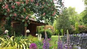 A garden with a wooden pergola, various flowering plants, and a seating area with chairs. - (101)Beautiful Apartment in Landmark Cotswold Grade II Listed Georgian House -  (Nailsworth)