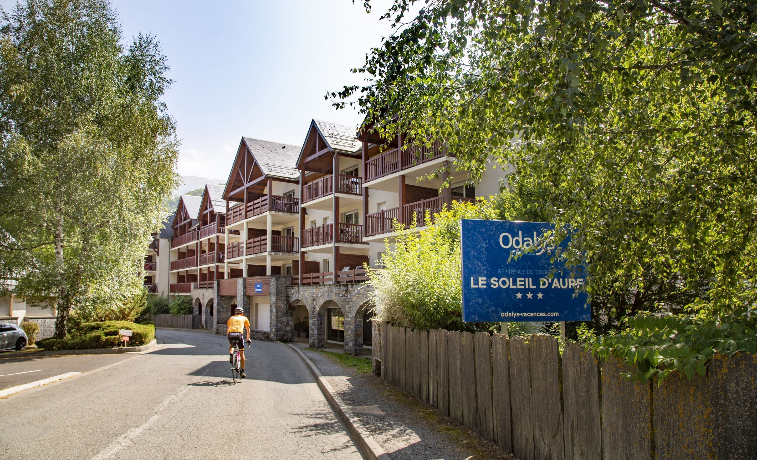 A hotel with a signboard advertising 'Le Soleil d'Aur', featuring a multi-story building with balconies and a stone facade.