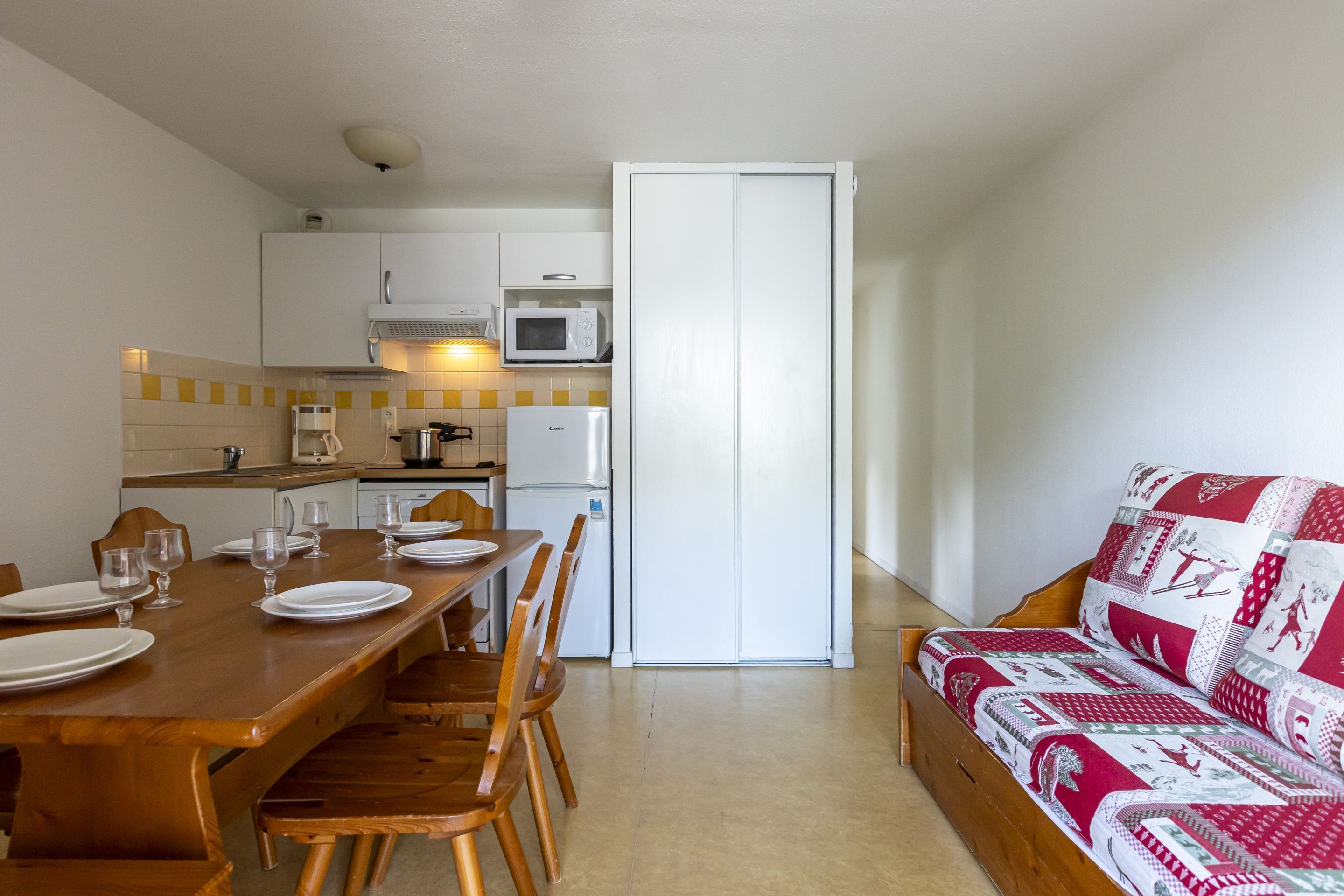 A compact living space with a dining area, kitchenette, and a sofa.