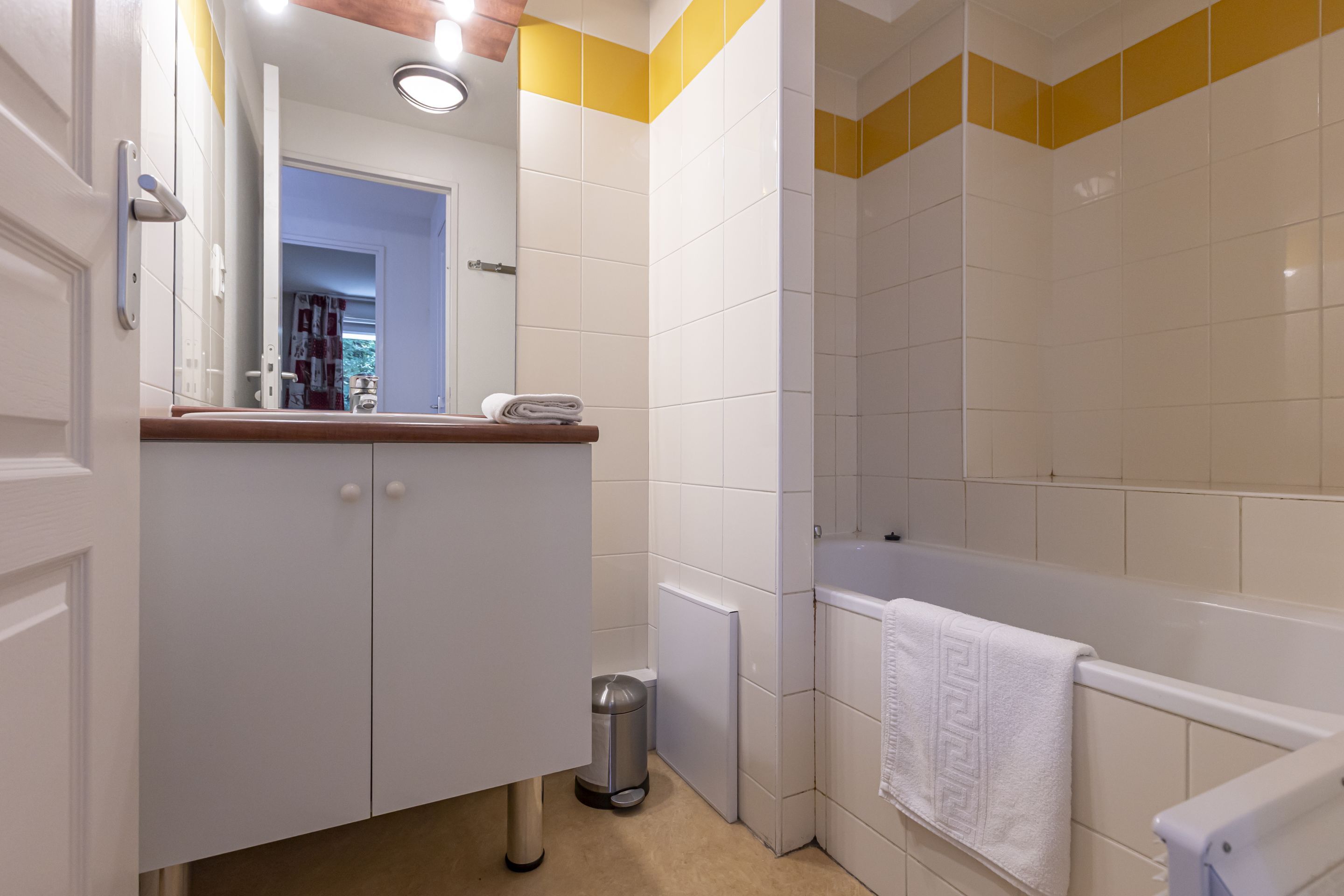 Ein Badezimmer mit weißem Waschtisch, einem Spiegel, einem Handtuch, einer Toilette und einer Badewanne.