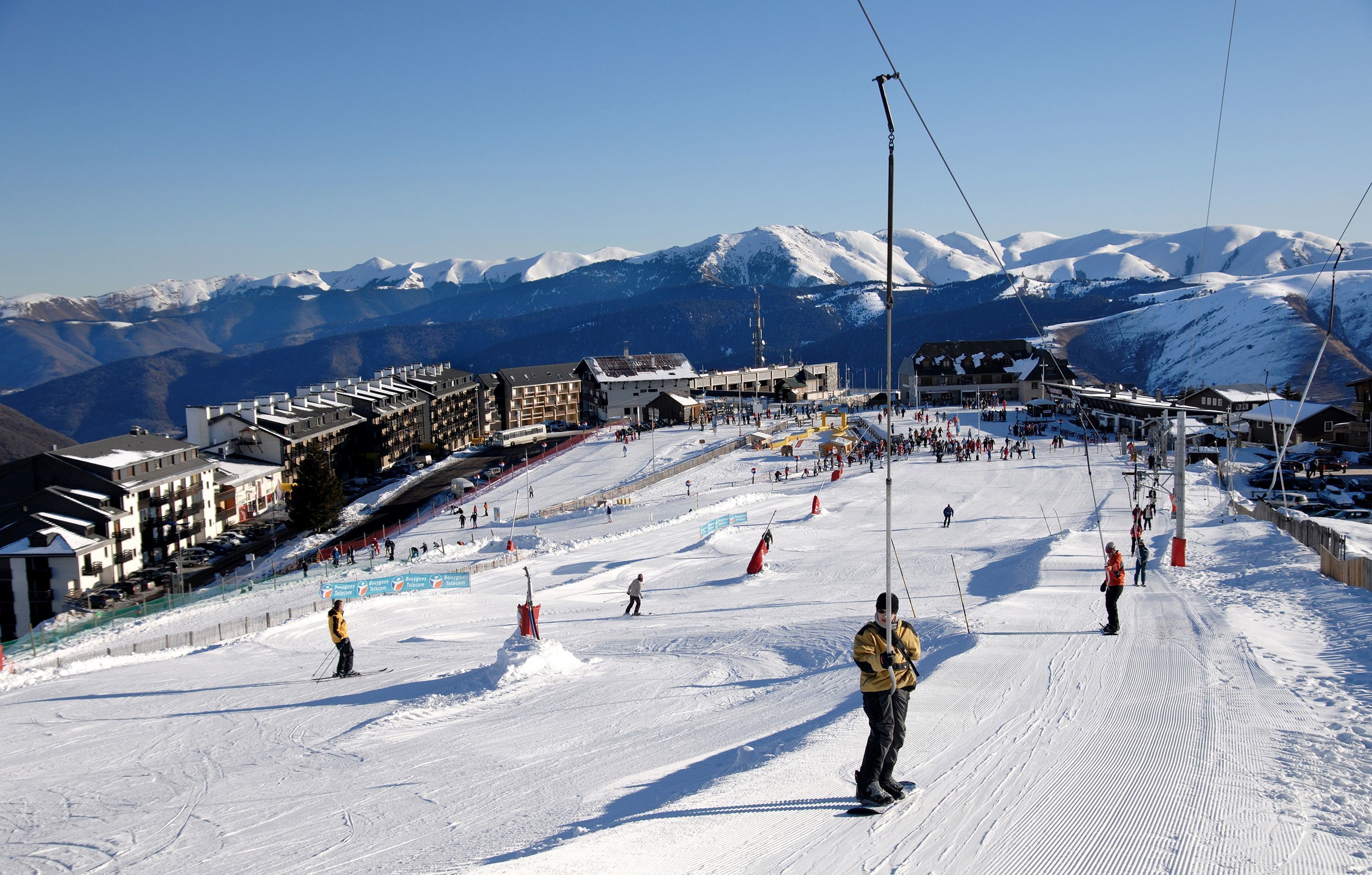 A ski resort with multiple buildings, a ski slope, and a mountain backdrop.