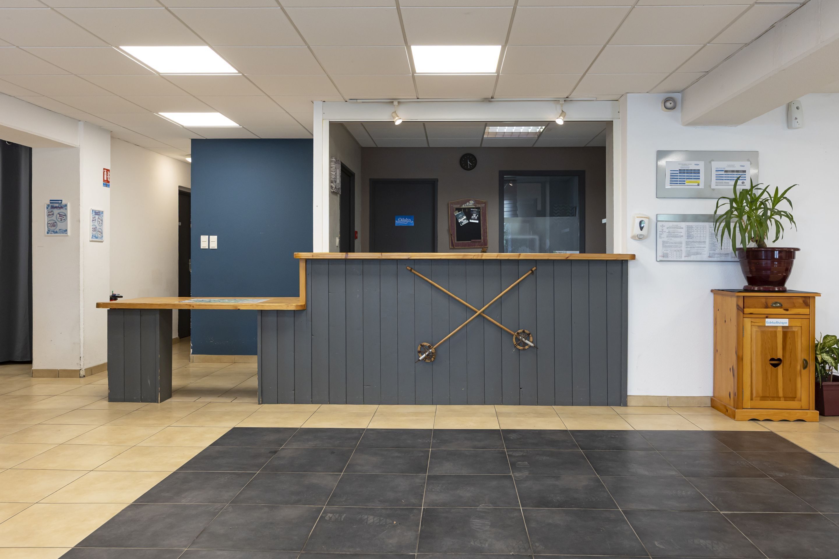 A reception area with a reception desk, a clock, and a potted plant.