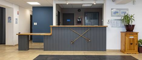 A reception area with a reception desk, a clock, and a potted plant.
