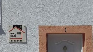 A white door with the number 1, a small mailbox, and a rural house sign on a textured wall.
