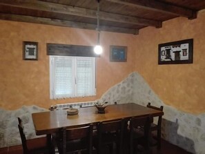 Un coin repas avec une table et des chaises en bois, une fenêtre avec des stores et un luminaire au plafond.