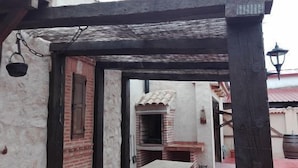 A covered outdoor area with a brick wall, a table, and a hanging basket.