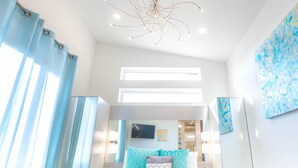 Un dormitorio moderno con una cama grande, un aplique de techo y un ventanal amplio.