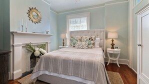 A bedroom with a bed, a fireplace, a ceiling fan, and a window with blinds. - Private Parking and Unbeatable Location on Liberty Street by Lucky Savannah (Savannah)
