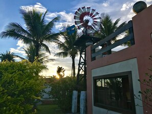 A windmill, palm trees, and a building with a window. - Pousada Icaraí - Ilha Comprida (Ilha Comprida)
