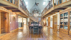 A spacious dining area with a high ceiling, wooden floors, and a central chandelier. - 9 Mi to Boyne Resort! Farmhouse Near Town & Lake (Harbor Springs)