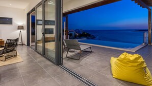 Ein modernes Wohnzimmer mit Glastür und Zugang zu einem Balkon mit Blick auf ein Gewässer.