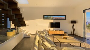 Ein modernes Wohnzimmer mit einer Couch, einem Couchtisch, einem Fernseher und einer Treppe.