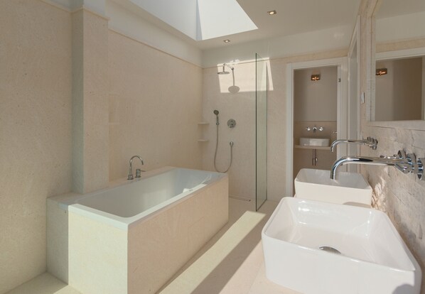 A modern bathroom with a large bathtub, a glass-enclosed shower, and a vanity with a sink.