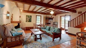 A cozy living room with a wooden ceiling, a fireplace, a sofa, and a dining area.