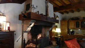A cozy room with a fireplace, wooden furniture, and a kitchen area.