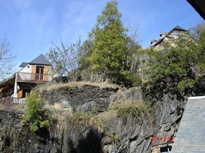 A house built on a rocky hillside with a stone wall and a wooden structure. - Cottage Gîte familial Fouga for 8 people (Bareilles)