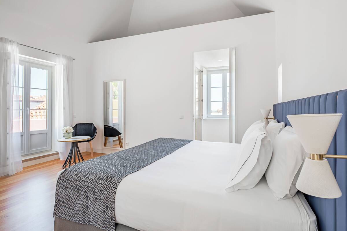 Un dormitorio con una cama grande, una silla, una mesita y vistas al exterior.