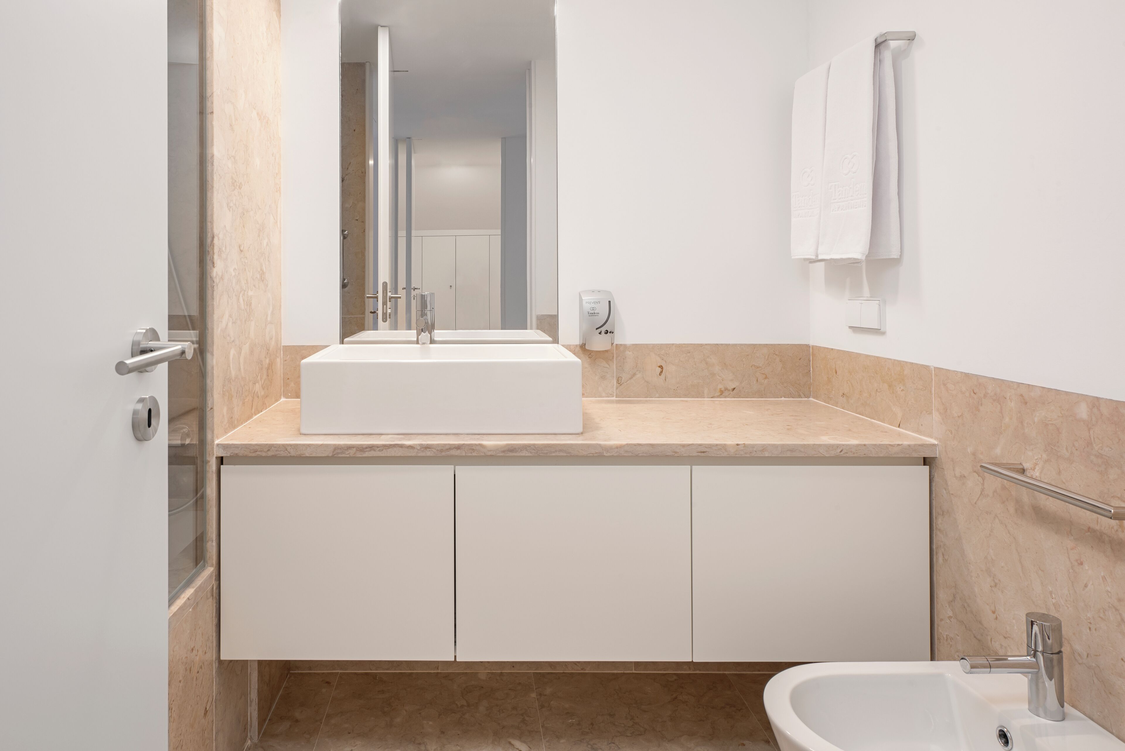 A modern bathroom with a large white sink, a mirror, and a bidet.