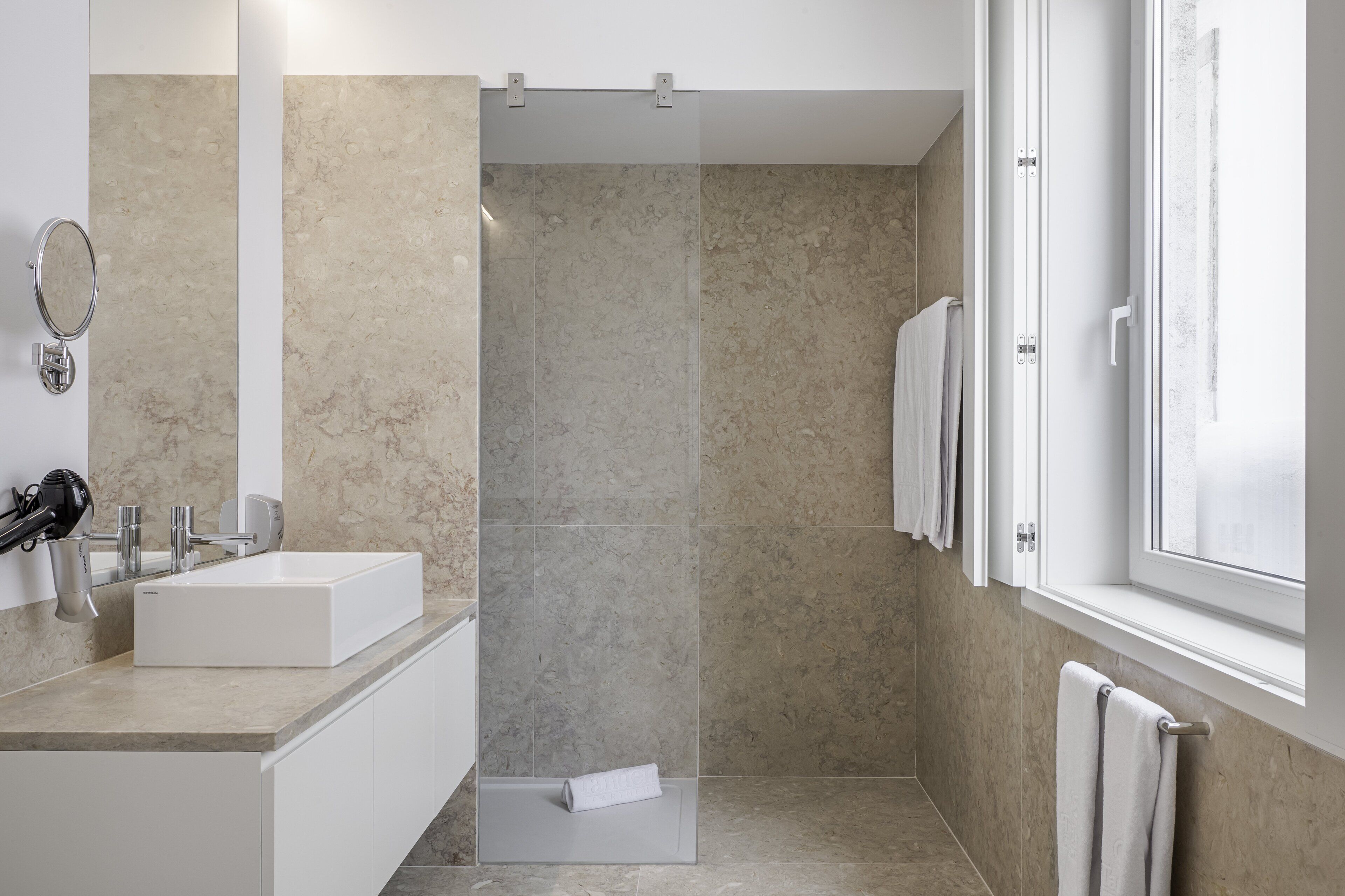 Un baño moderno con un lavamanos grande, espejo y zona de ducha.