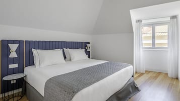 Une chambre à coucher bien rangée, avec un lit, des tables de chevet et une fenêtre avec des rideaux.