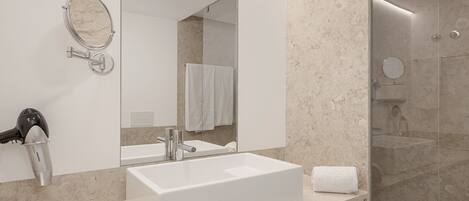 Un bagno moderno con uno specchio grande, un lavandino bianco e un asciugacapelli.