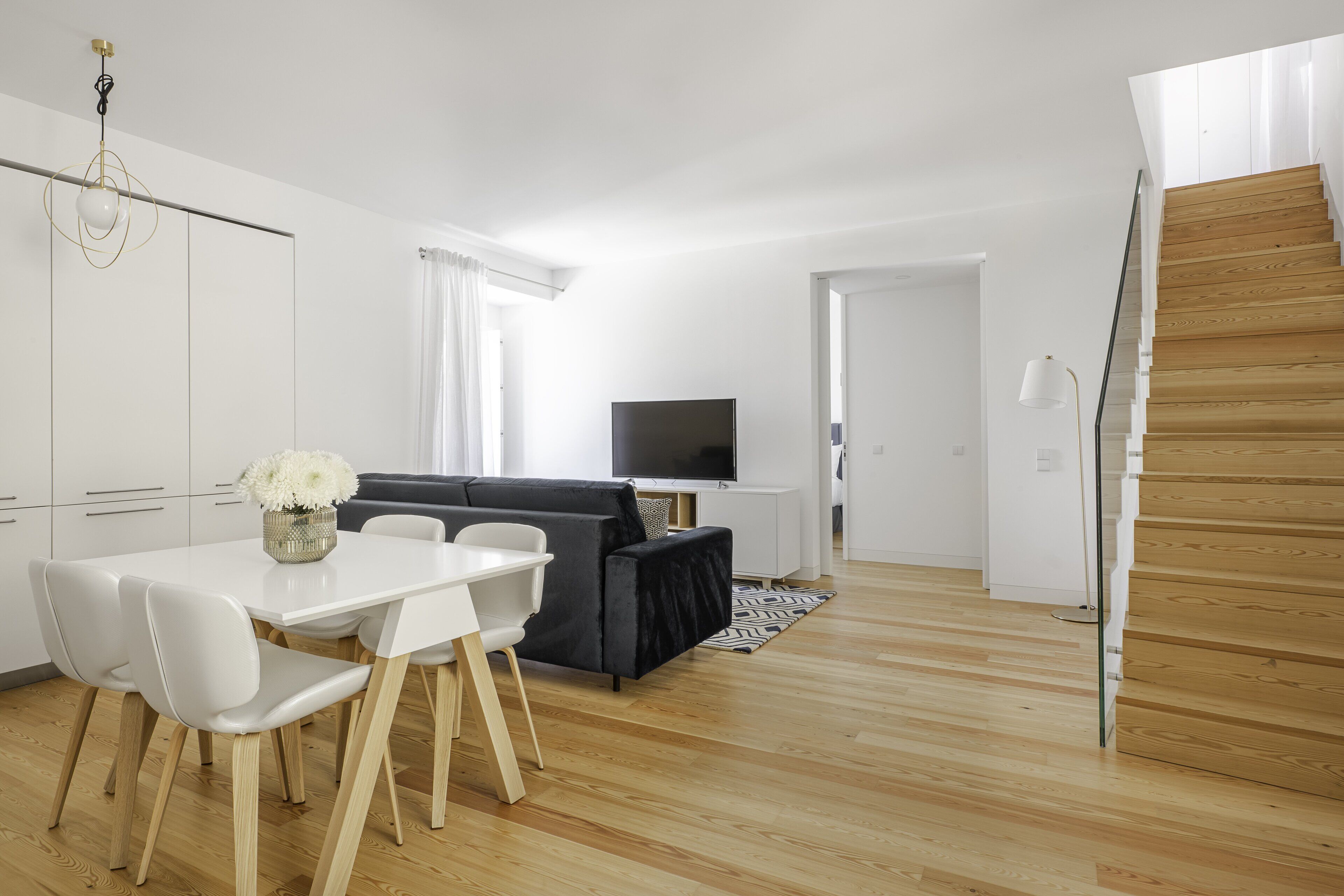 Una sala de estar moderna con un sofá, televisor y comedor.