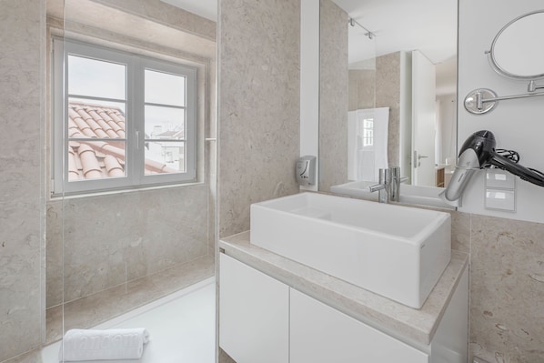 Un baño moderno con un ventanal grande, un lavamanos blanco y un espejo.