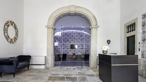 Un hall con una mesa de recepción, un sofá y un papel tapiz estampado.